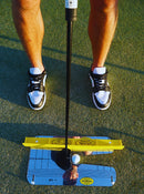 Person practicing golf putting on a green with a putter and ball.